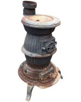 A cast iron pot-bellied stove of ribbed form with adjustable side vent and flu, supported on