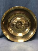 An arts and crafts circular brass alms dish, the central boss with lion rampant framed by flower