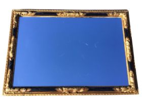 A rectangular wall mirror, the ebonised gilt frame with foliate scrolled mounts, enclosing a