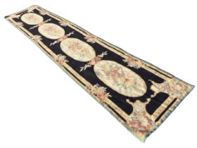 A Victorian style woolwork runner, the black ground with four oval floral medallions and