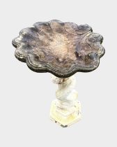 A painted composition stone garden birdbath with scalloped shell shaped bowl on dolphin tail support