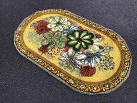 A 60s handmade latch hook wool rug, the mustard field with large floral spray, within a scrolling