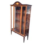 An Edwardian mahogany display cabinet, the arched pediment inlaid with an oval fan medallion,