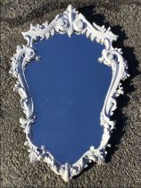 A rococo style painted wall mirror, the foliate scrolled frame with silvered and gilt highlights,