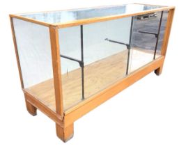 A 1930s oak and beech display counter, the rectangular glazed top above two sliding glass doors