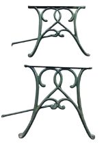 A cast iron table base with two waisted sections joined by tubular rails, each piece with scrolled