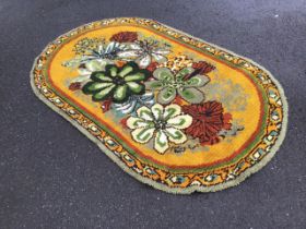 A 60s handmade latch hook wool rug, the mustard field with large floral spray, within a scrolling