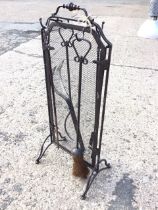 A wrought iron fireside companion set with mesh sparkguard with knopped handle supporting tongs,