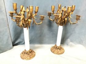 A pair of decorative candelabra with ceramic columns on circular scroll cast bases, each