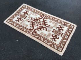 A 60s Turkish style handmade latch hook wool rug, the ivory field with diamond lozenge amid