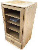 An Ercol elm cabinet with hinged rectangular top opening to a compartment, above a bevelled glazed