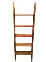 A five-rung library ladder, the treads decorated with whiskey advertising brands. (52in)