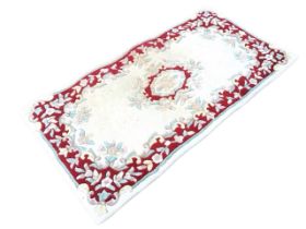 An Indian Aubusson style wool rug, the cream field with floral medallion, within a flower and