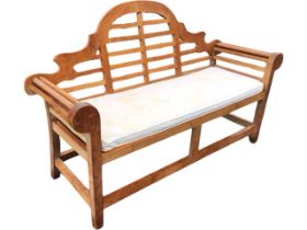 A hardwood Lutyens style garden bench, with shaped arched back above a slatted seat with squab