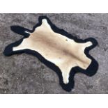 An animal skin rug on black baize ground. (31in x 47.5in)