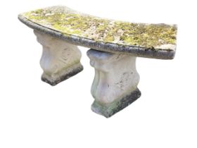 A composition stone crescent shaped garden bench with moulded slab seat on twin scrolled supports
