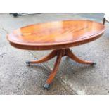 An oval mahogany coffee table with moulded top on tapering column above quadripartite sabre legs