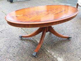 An oval mahogany coffee table with moulded top on tapering column above quadripartite sabre legs