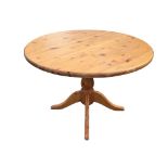 A contemporary circular pine table supported on bulbous column with quadripartite moulded sabre
