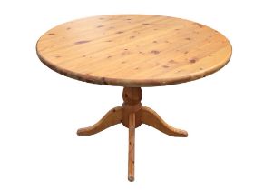 A contemporary circular pine table supported on bulbous column with quadripartite moulded sabre