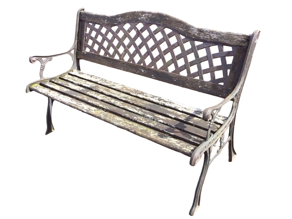 A garden bench with latticework arched metal panel to back above a wood slatted seat, the scrolled
