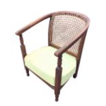 A 20s beech low armchair with caned horseshoe shaped back, and arms on turned supports, above a