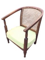 A 20s beech low armchair with caned horseshoe shaped back, and arms on turned supports, above a