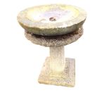 A composition stone birdbath with circular bowl on an associated panelled square tapering column