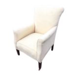 An Edwardian upholstered armchair with arched back and rectangular sprung seat flanked by