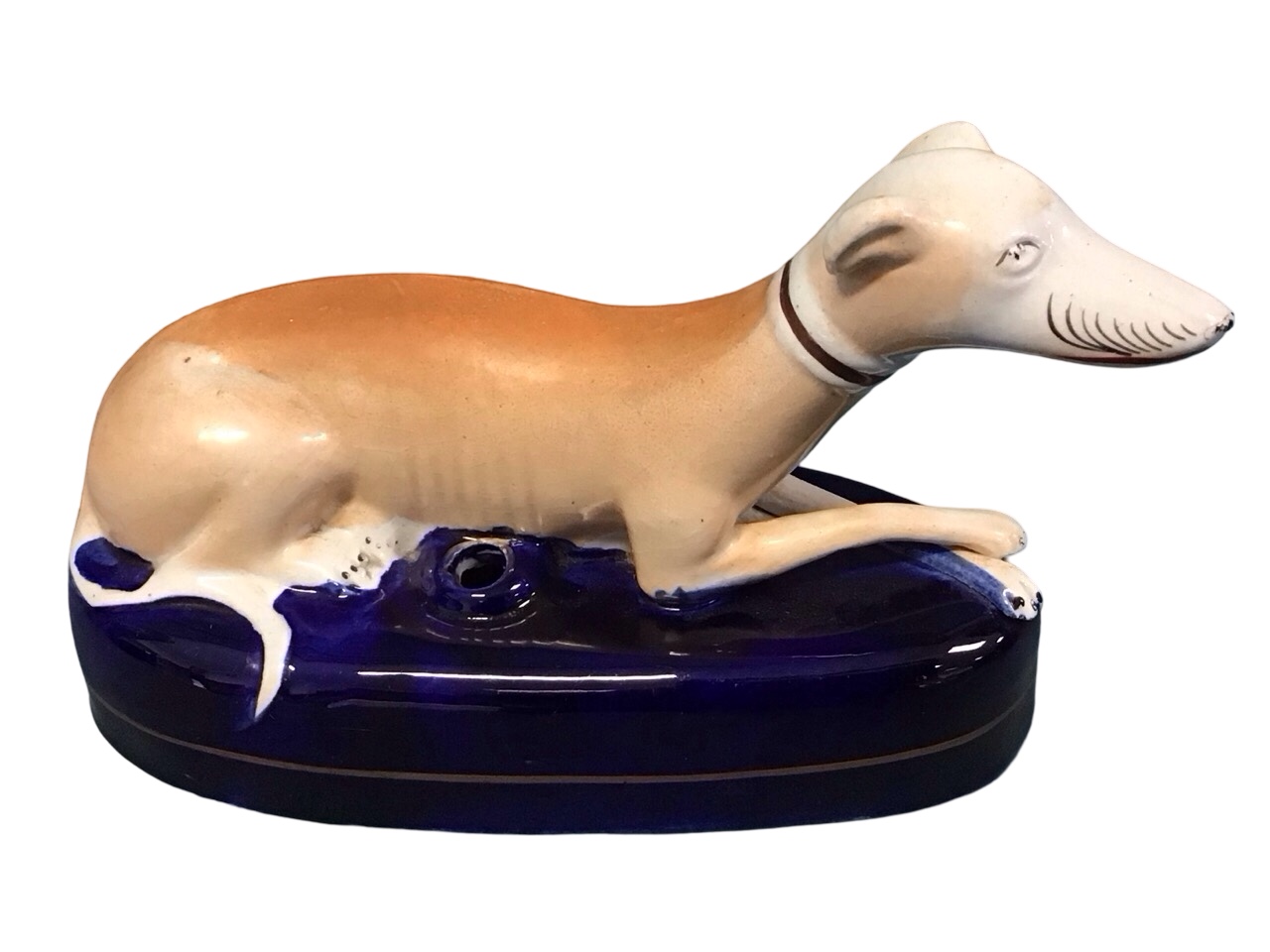 A Staffordshire ceramic inkwell in the form of a recumbent greyhound on an elliptical blue glazed