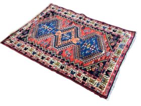 A Shiraz style camel hair rug with three hooked medallions on a red field with flowerhead