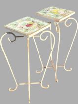 A pair of wrought iron plant stands with square handpainted tile tops decorated with fruit, raised