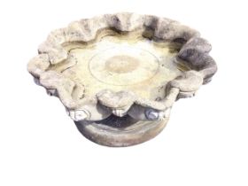 A circular composition stone garden birdbath, the scalloped bowl cast with scrolled shell medallions