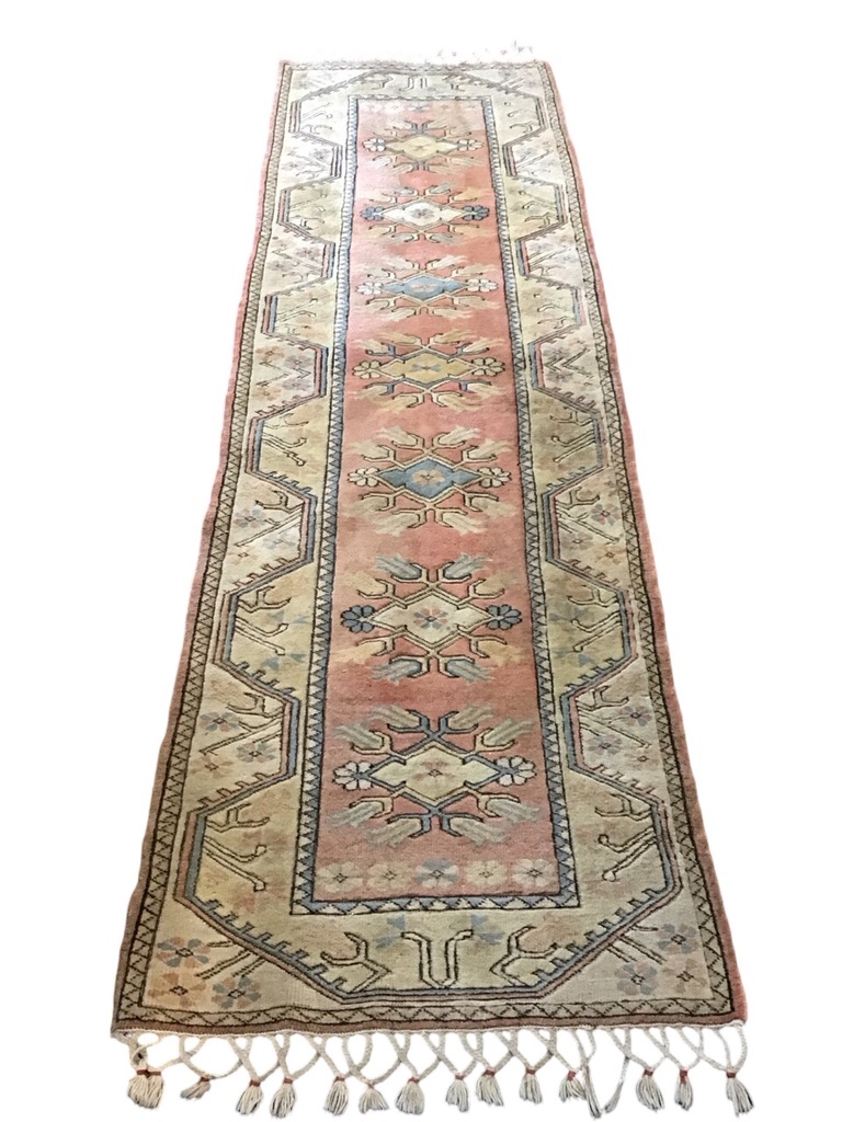 A Turkish wool runner with floral lozenges on a pink field within stylised meandering floral