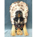 An Amazonian Indian hardwood wall mask decorated with coloured beads and seeds, scales, piranha
