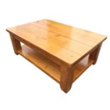 A substantial pine coffee table with rectangular four plank top raised on square legs joined by an
