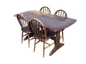 An Ercol elm dining table with rounded rectangular top on shaped trestle supports joined by a
