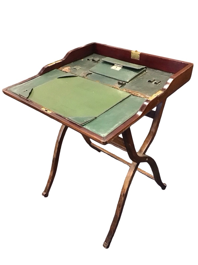 An Edwardian mahogany campaign writing desk with panelled sides and brass fittings enclosing a