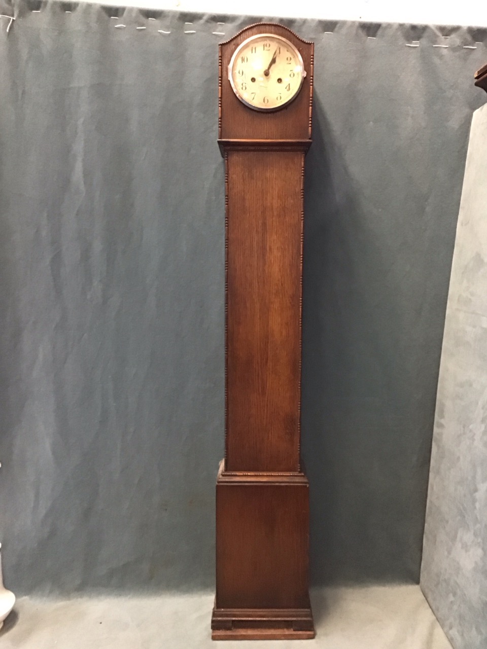 A 30s oak hood grandmother clock with reel & bead applied vorders, having arched above a circular