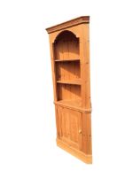 A Victorian style pine corner cabinet with moulded cornice above open shelves and a knobbed