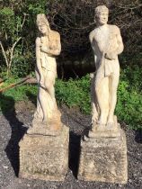 A pair of classical composition stone garden statues with a draped couple standing by logs on square