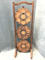 An Edwardian Indian carved hardwood folding three-tier cakestand with zigzag carved arched handle