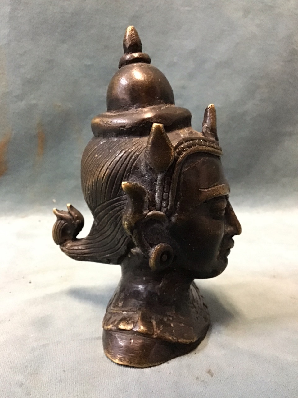 A small Burmese patinated brass bust of a buddhist deity with a serene expression wearing an - Image 2 of 3