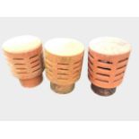 Three terracotta chimney cowls of tubular form with domed tops above slit-vented bodies. (13.5in) (