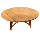 A contemporary circular hardwood dining table with plank top in a tripod base with curved tapering