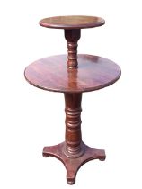 A two-tier stained pine table with graduated moulded circular tops on turned columns above a