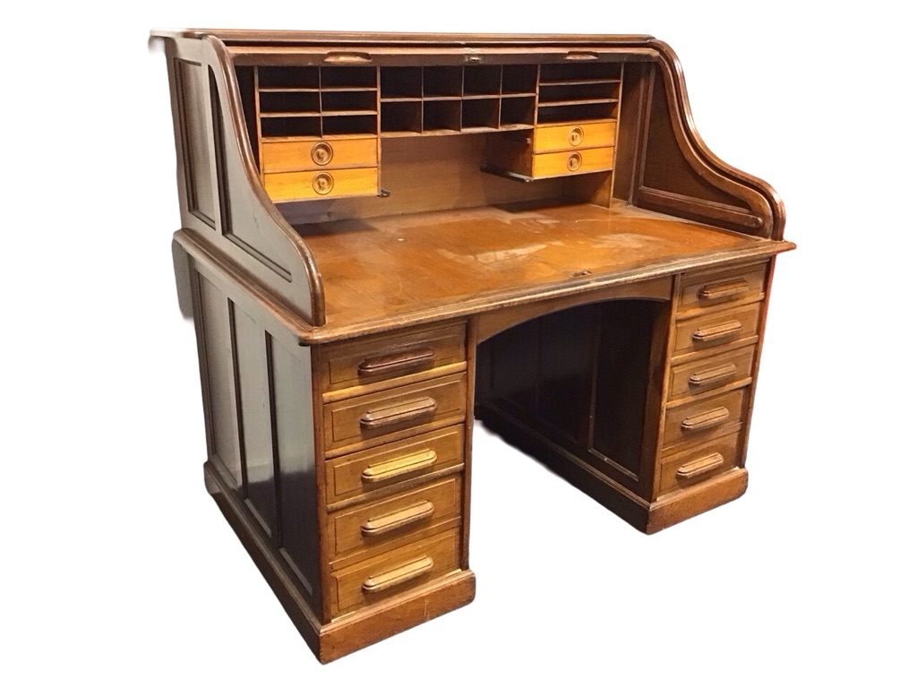 An Edwardian mahogany rolltop desk with panelled sides and tambour front enclosing pigeonholes and