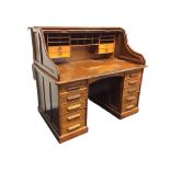 An Edwardian mahogany rolltop desk with panelled sides and tambour front enclosing pigeonholes and