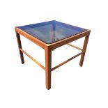 A 70s square mahogany coffee table with smoked glass top raised on chamfered and grooved square legs