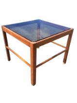 A 70s square mahogany coffee table with smoked glass top raised on chamfered and grooved square legs